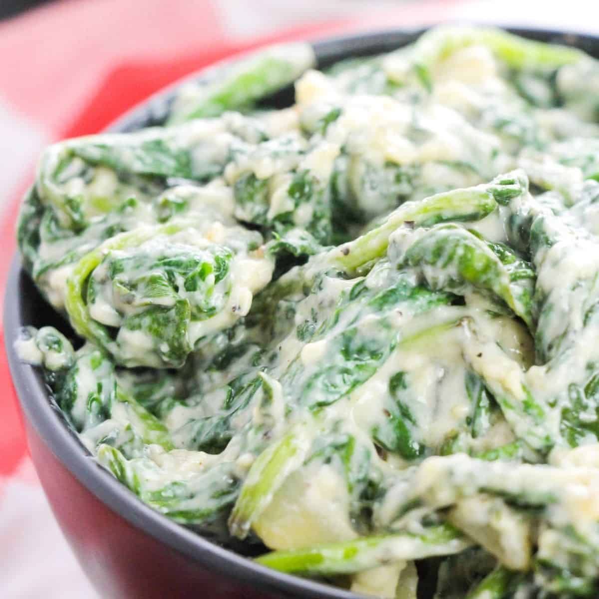 Luscious creamed spinach in a white serving bowl with a golden brown cheese crust and fresh chives